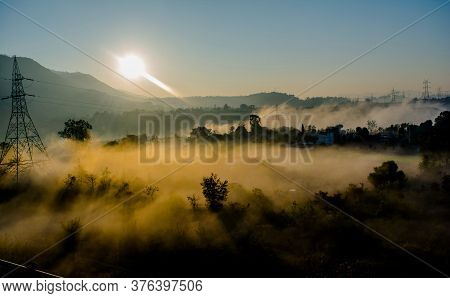 sun rays coming through the trees and electric towers with fog enhancing the light at sunrise, Aeria