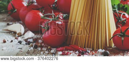 Italian Dry Pasta Spaghetti With Tomatoes And Fresh Herbs On A Dark Wooden Background, Selective Foc