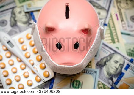 Piggy Bank In A Mask On A Background Of American Currency.the Concept Of Coronavrius Epidemic