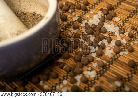 Ground Black In A Ceramic Mortar And Black And Coarse Salt Scattered On A Reed Mat. Close Up.
