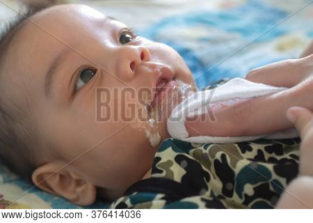 Asian Mother Is Wiping Her Baby's Face After Infant Baby Boy Vomiting. People And Family Lifestyle C