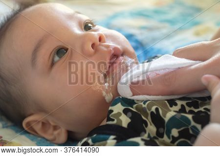 Asian Mother Is Wiping Her Baby's Face After Infant Baby Boy Vomiting With Soft Sunbeam. People And 