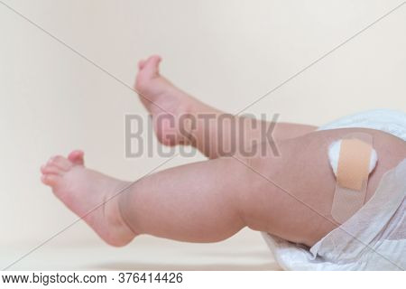 Baby Boy Legs With A Band-aid Patch After Taking A Vaccine. Doctor Or Nurse Putting Plaster On Baby 