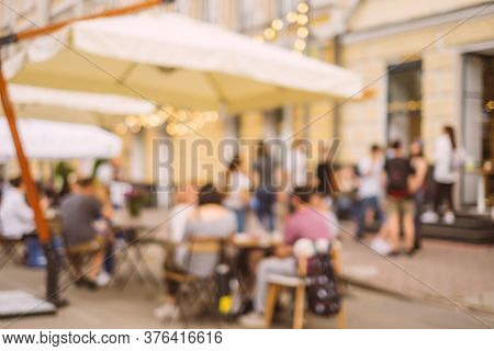 Blurred Background With Group Of Peolple Sitting At The Cafe Veranda Outside.
