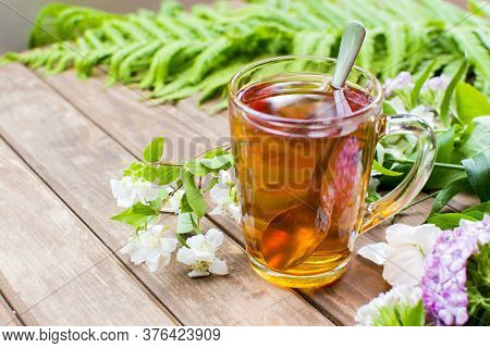 Green Tea Cup With Teaspoon And Floweer Buds On Old Wooden Table, With Copy Space. Summer Menu Conce