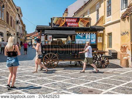 Brasov/romania - 06.28.2020: Walking Street In The Old Town Of Brasov. A Kurtos Kolacs Stand On Whee
