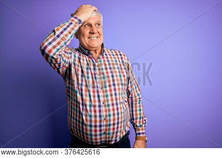 Senior handsome hoary man wearing casual colorful shirt over isolated purple background smiling confident touching hair with hand up gesture, posing attractive and fashionable