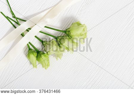 Bunch Of White Eustoma On Light Wooden Background With Copy Space. Floral Greeting Card. Top View.