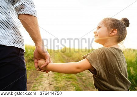 Road To Life. Dad Taking His Little Daughter Gently By The Hand, Giving Her Warm, Safe, Protected An