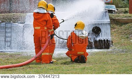 Firefighter Fighting With Flame Using Fire Hose Chemical Water Foam Spray Engine. Fireman Wear Hard 
