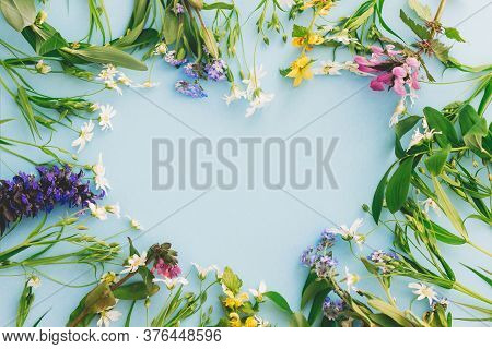 Happy Mother's Day Concept. Floral Heart Shape Of Spring Wildflowers Flat Lay On Blue Paper Backgrou