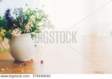 Wildflowers Bouquet In Old Cup On Wooden Table,  Space For Text. Blooming Spring Flowers In Soft Lig