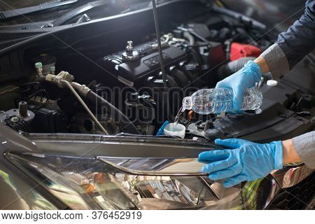 Car Maintenance, Mechanic Is Adding Water To Engine, Close-up.