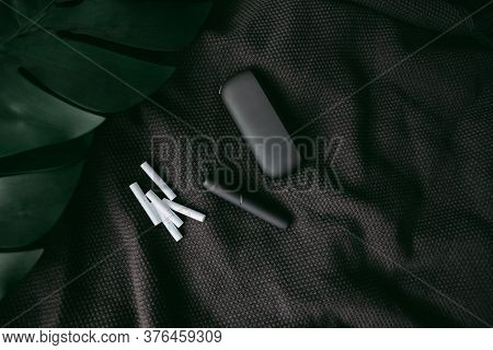 Iqos On The Dark Background With Grean Tropical Leaves. Heating Tobacco Technology . High Quality Ph