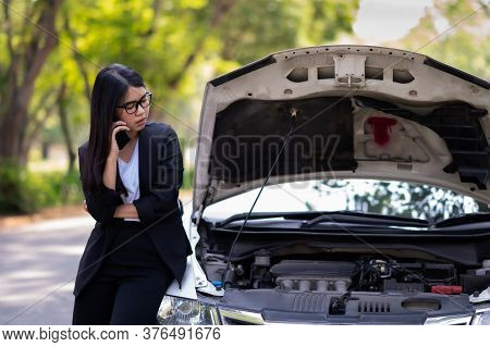 A Young Asian Woman Is Calling Her Service Technician To Fix A Broken Car On The Side Of The Road, D