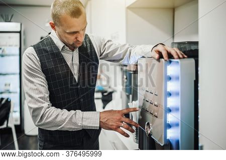A Businessman In A Plaid Vest Is Choosing Which Type Of Coffee To Make And He Is About To Push One O