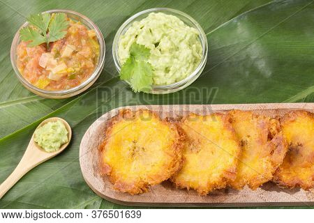 Patacón Fried Pieces Of Crushed Green Banana. Guacamole. On The Wooden Table (tostón, Tachino)