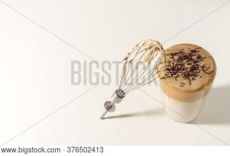 Coffee Dalgon On A Light Pastel Background. The Foam Is Sprinkled With Chocolate Chips. Nearby Is A 