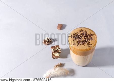 Coffee Dalgon In A Glass Cup On A Gray Background. The Foam Is Sprinkled With Chocolate Chips. Chunk
