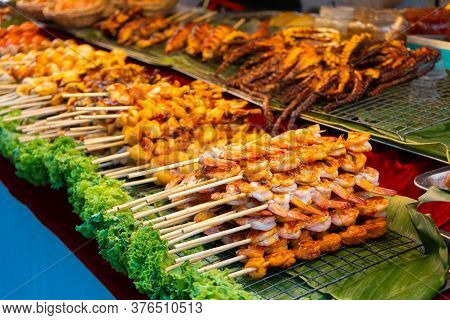 Street Food Market In Asia. Food Counters, Mini Barbecue On A Stick Also Called Satey