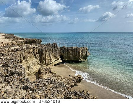 A Rocky Beach With Clear Turquoise Water In Stuart, Fl On A Sunny Day.