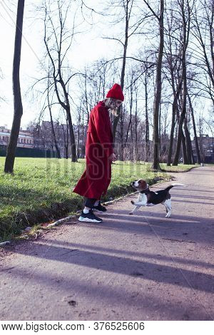 Pretty Young Girl In Redd Coat Playing With Dog Outside In Green Park, Lifestyle People Concept