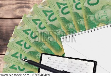 20 Canadian Dollars Bills Fan And Notepad With Contact Book And Black Pen. Concept Of Financial Plan