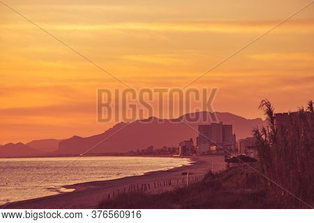 Sunrise Over Sea. View From Gandia Beach, Valencia Spain. Montgo Mountain Massif Silhouetted On Hori