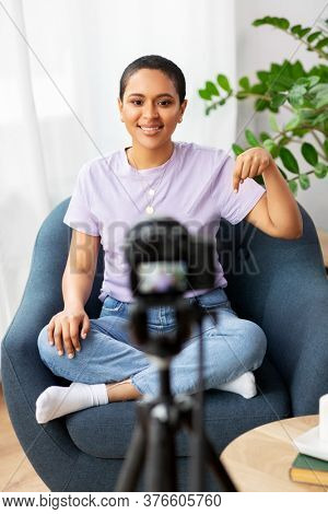 blogging, videoblog and people concept - happy smiling african american female video blogger with camera videoblogging at home
