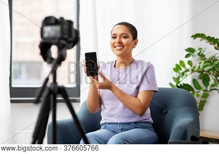 blogging, videoblog and people concept - happy smiling african american female video blogger with smartphone camera videoblogging at home