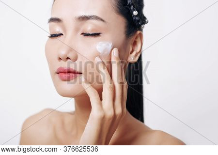 Young Asian Woman Closing Eyes And Applying Anti-aging Mosturizing Soft Cream O Her Face