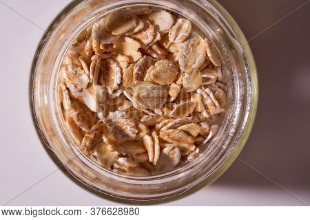 Oat Flakes Lie In A Snitch Jar On A White Background. Close-up. With Copy Space.
