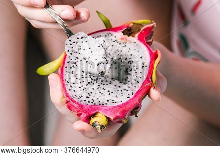 The Girl Is Eating A Tropical Fruit With A Spoon. Sweet And Fresh Nourished. Dragon Fruit Close-up.