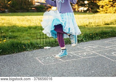Closeup Of Chld Girl Playing Jumping Hopscotch Outdoor. Funny Activity Game For Kids On Playground O