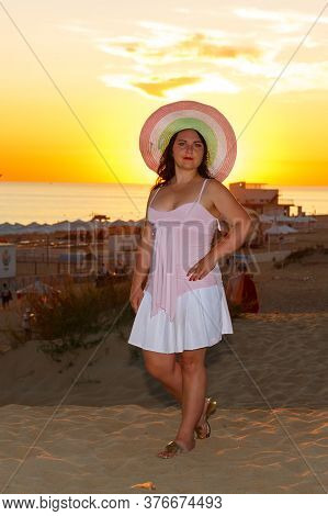 Jewish Woman In A Hat And White Dress At Sunset On A Background Of The Sea.
