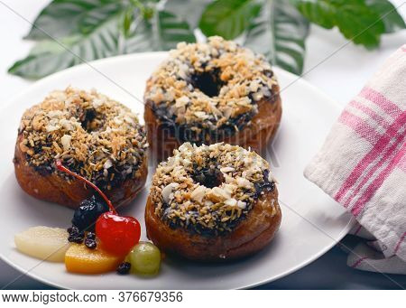Chocolate Donuts With Various Topping With Jerry Fruit On A Whitel Plate