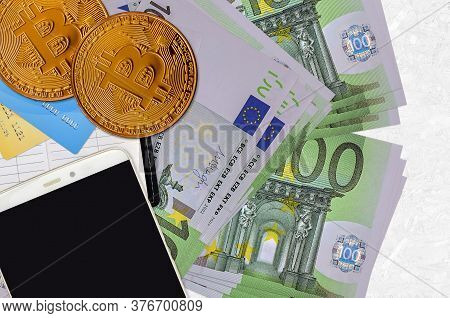 100 Euro Bills And Golden Bitcoins With Smartphone And Credit Cards. Cryptocurrency Investment Conce