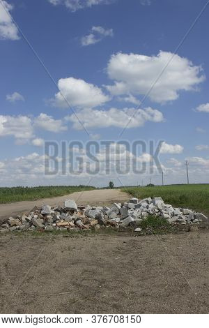 A Large Pit On A Poor Unsworned Rural Road Littered With Broken Brick Fragments, Stones, Constructio