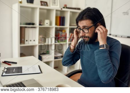 Close Up Portrait Of Young Bearded Male Teacher Adjusting Wireless Headphones While Giving Online Cl