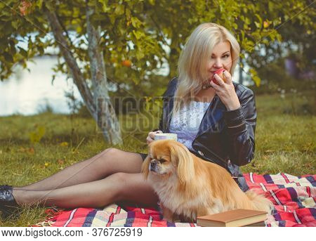 Middle Age Stylish Blonde Hair Pretty Woman Dressed In Leather Black Jacket  In Autumn Garden With P