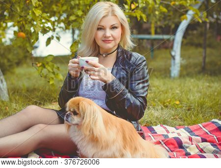Middle Age Stylish Blonde Hair Pretty Woman Dressed In Leather Black Jacket  In Autumn Garden With P