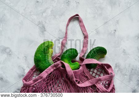 Trendy Ugly Vegetables. Fresh Ugly Cucumbers On A Blue, Concrete, Background In A String Bag. Imperf