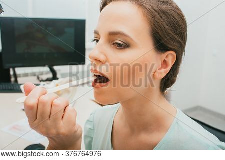 Pediatrician Using A Tongue Depressor To Examine A Womans Throat. Patient Woman Opening Her Mouth Lo