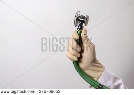 Green Stethoscope. A Doctor In A White Medical Uniform And Gloves Holds A Stethophonendoscope.