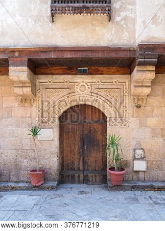 Facade Of Old Stone Bricks Decorated Wall With Arched Wooden Door