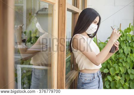 Beautiful Woman With Face Mask Is Holding Coffee In Front Of Coffee Shop