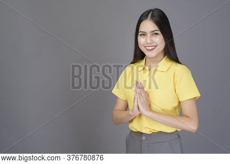 Beautiful Confident Woman Is Greeting (thai Wai) To Show Respect Over Grey Background Studio