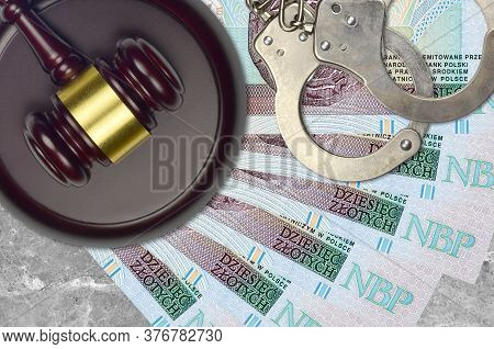 10 Polish Zloty Bills And Judge Hammer With Police Handcuffs On Court Desk. Concept Of Judicial Tria
