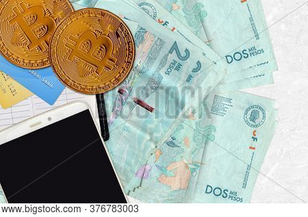2 Colombian Pesos Bills And Golden Bitcoins With Smartphone And Credit Cards. Cryptocurrency Investm