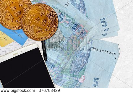 5 Ukrainian Hryvnias Bills And Golden Bitcoins With Smartphone And Credit Cards. Cryptocurrency Inve